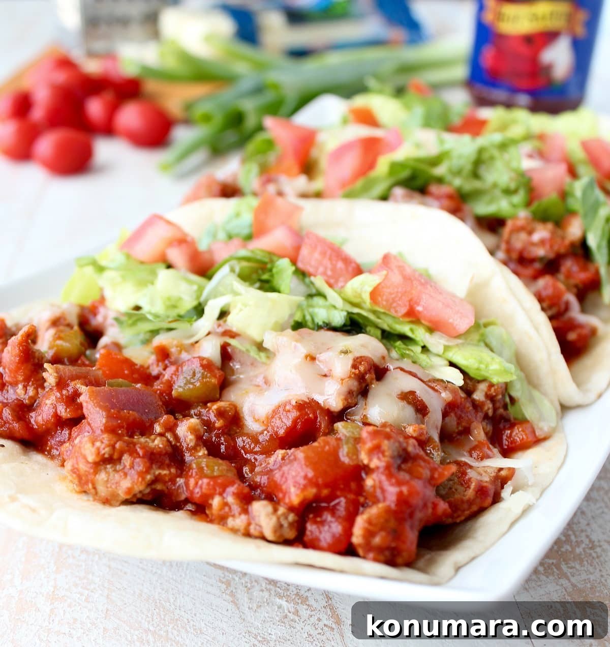 A flour tortilla topped with ground turkey, salsa, cheese, lettuce, and tomato.