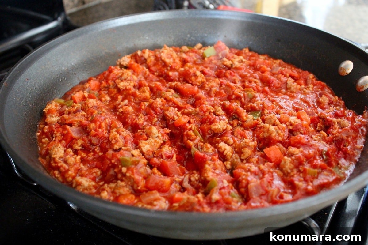 Ground turkey in a red sauce cooking in a skillet.