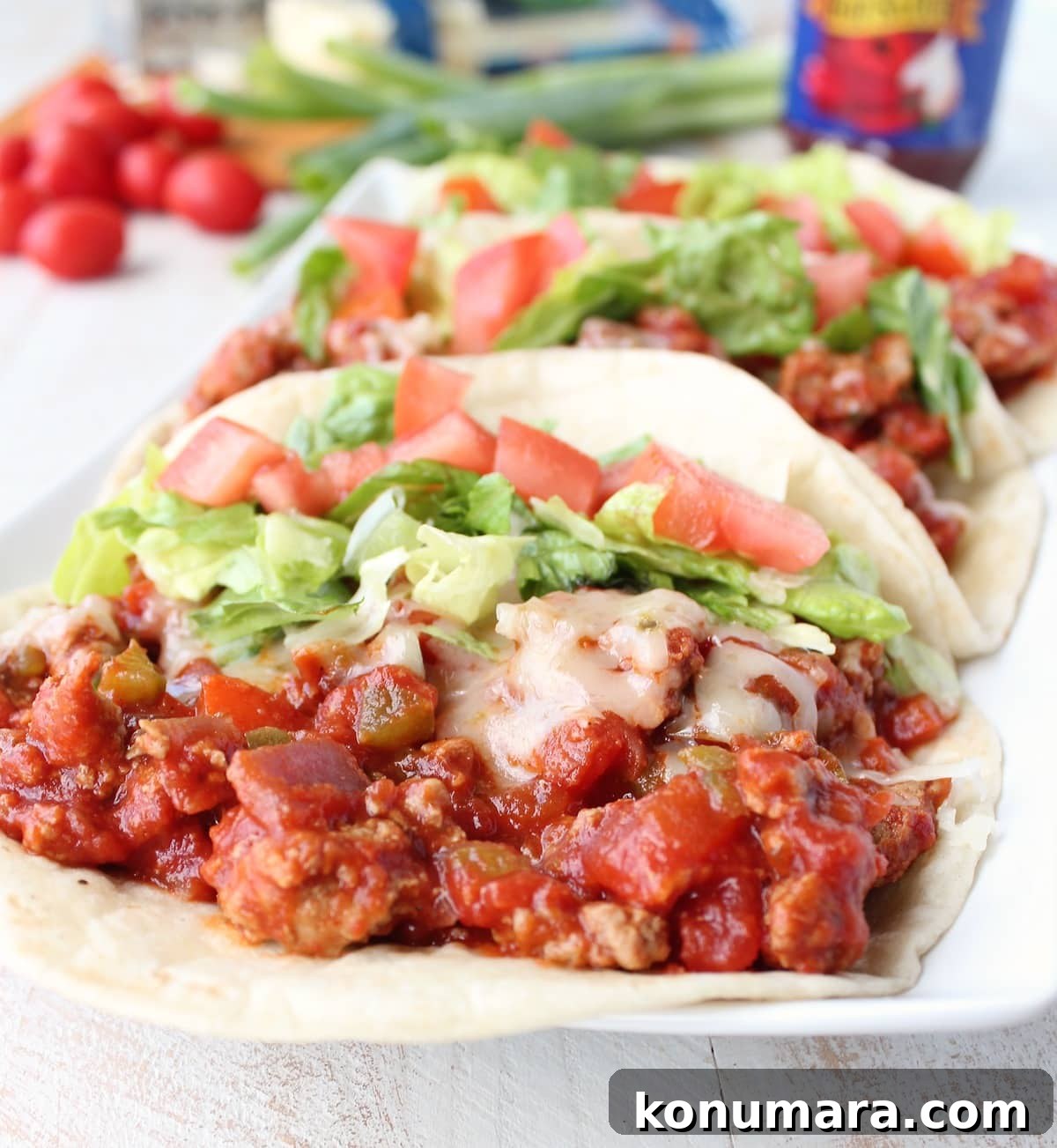 A flour tortilla filled with ground turkey in a red sauce topped with lettuce and tomatoes.