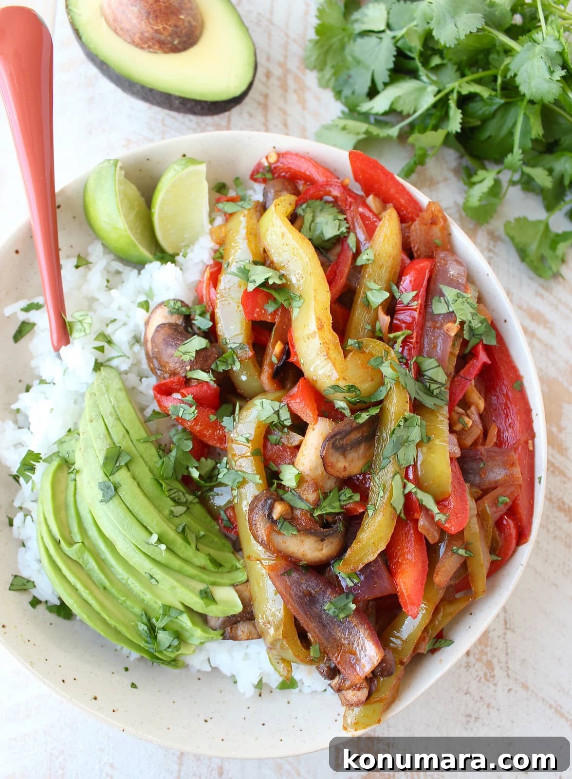 Vegetarian Fajita Rice Bowl with Peppers and Black Beans 2 fajita bell peppers, onions and mushrooms in bowl with rice and sliced avocado