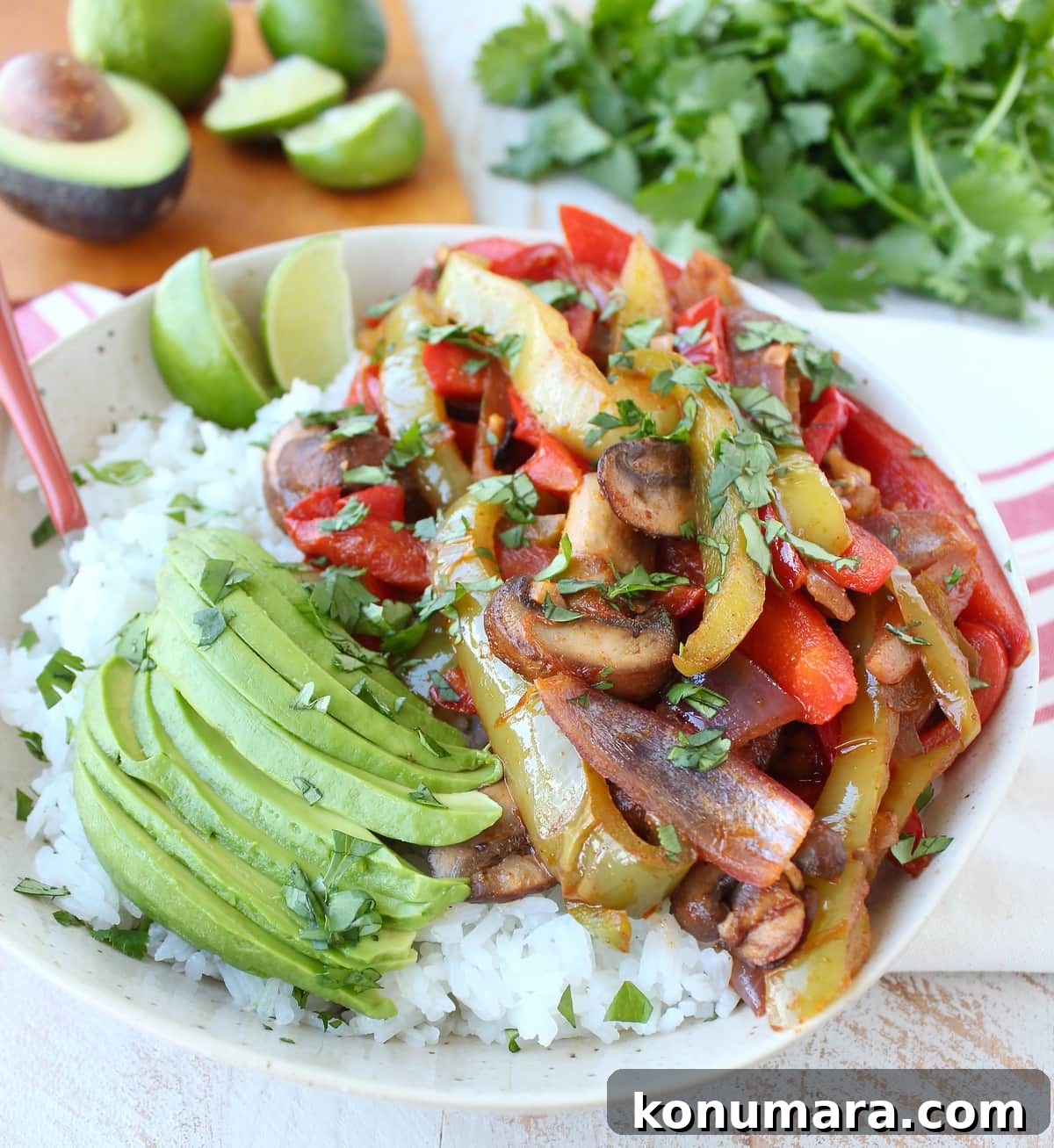 Vegetarian Fajita Rice Bowl with Peppers and Black Beans 6 fajita veggies and sliced avocado on top of cooked white rice in a bowl