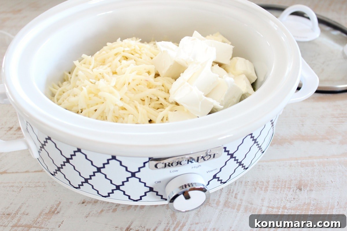 Cubed cream cheese and shredded pepper jack cheese in crock pot