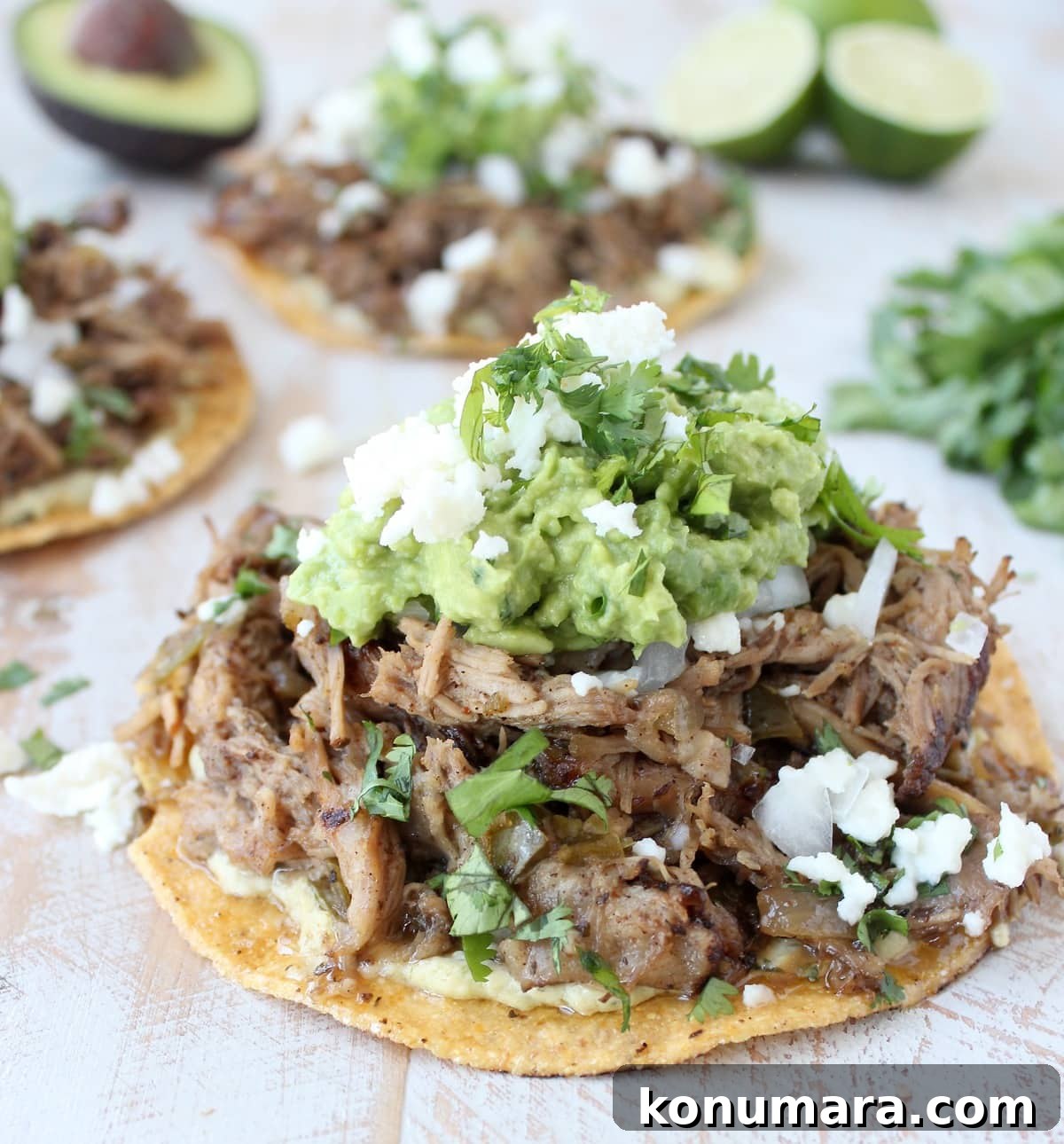 shredded carnitas pork on tostada shell, topped with guacamole and cotija cheese