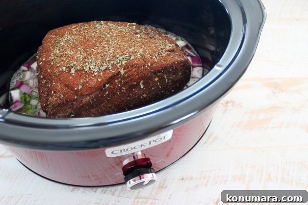 spice rubbed pork shoulder in Crock Pot with diced onions and peppers