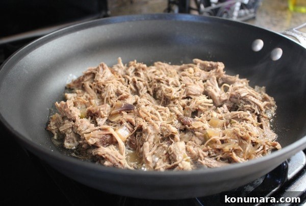 shredded pork cooking in oil in large skillet on the stove