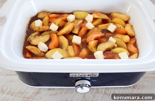 cooked sliced fruit in a crock pot with sugar and cubes of butter