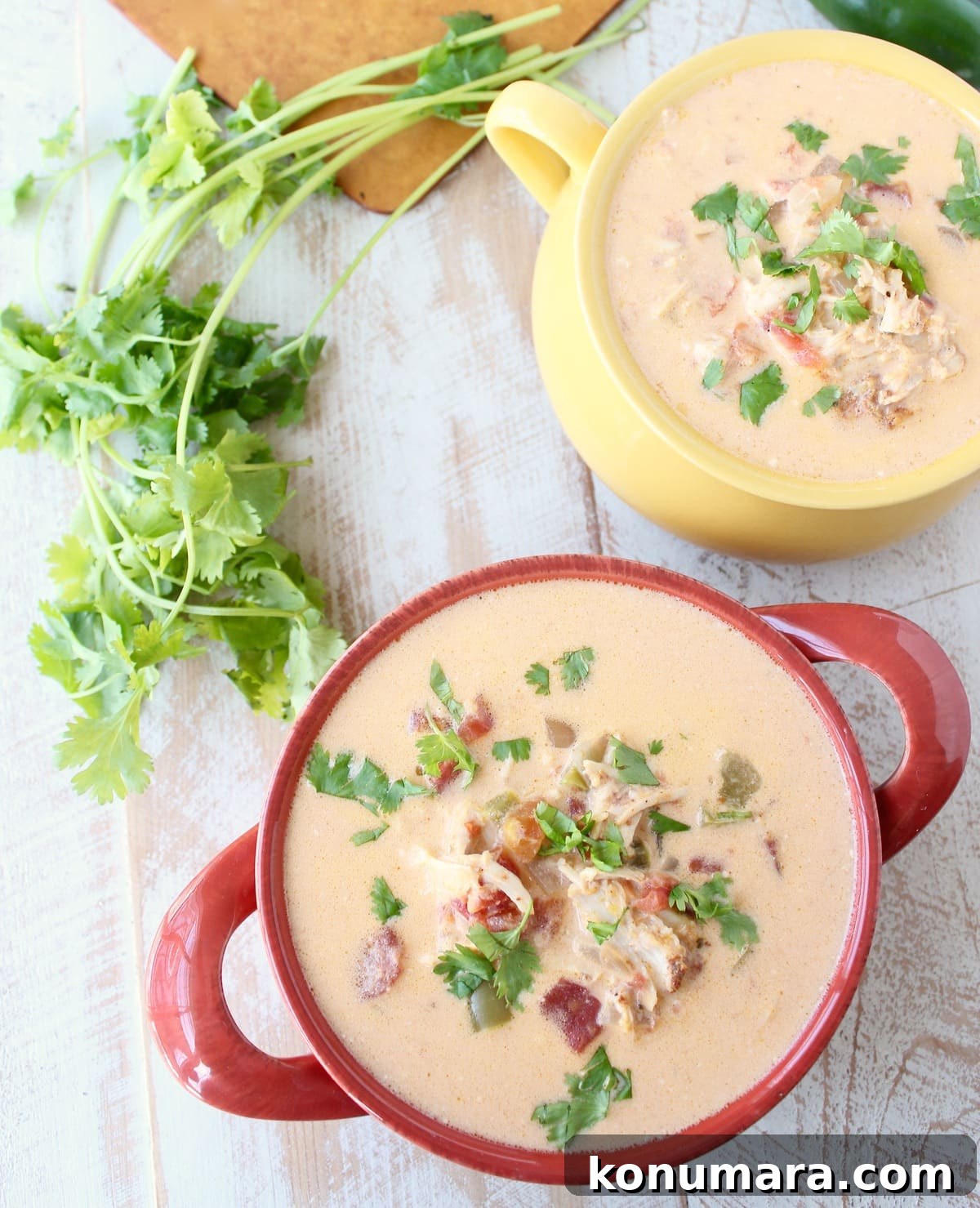 Slow Cooker Cheesy Turkey Taco Soup Recipe 7 Two bowls on a wooden surface filled with Cheesy Turkey Taco Soup.