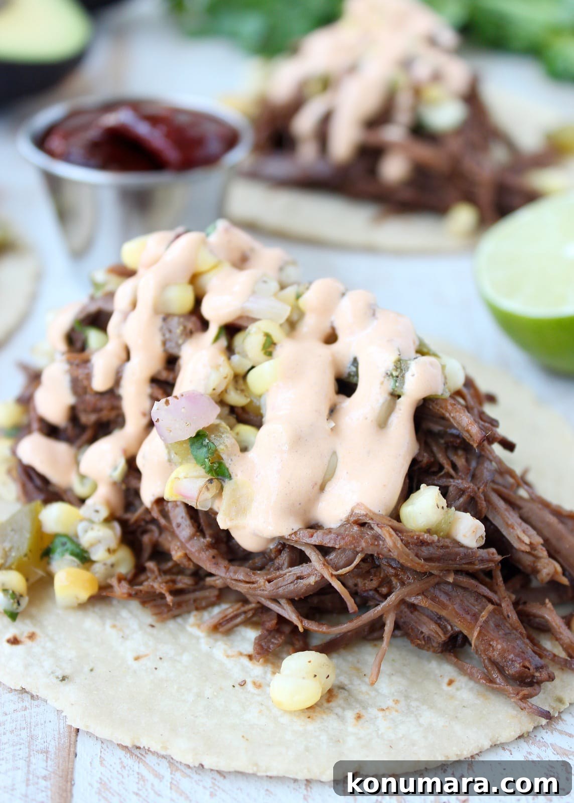 Slow Cooker Smoky Chipotle Brisket Tacos 6 shredded brisket on a tortilla topped with corn salsa and chipotle sauce