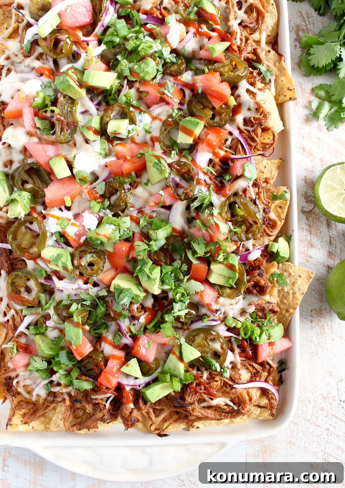 Loaded Pulled Pork Nachos Recipe with Tangy BBQ Sauce 5 Pulled Pork Nachos on a baking sheet on a wooden surface.
