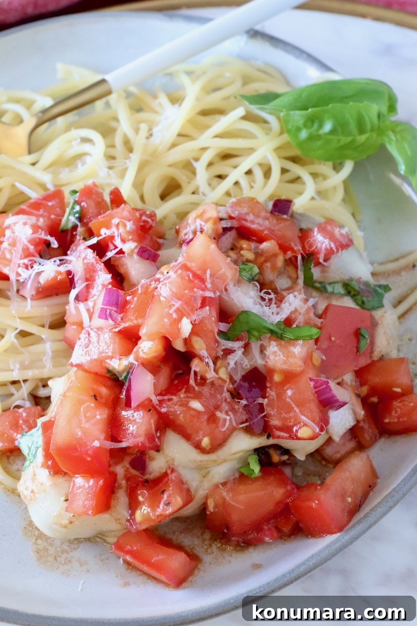 Bruschetta Chicken Recipe with Basil and Balsamic Glaze 2 cooked chicken on a plate next to spaghetti noodles covered with tomato bruschetta