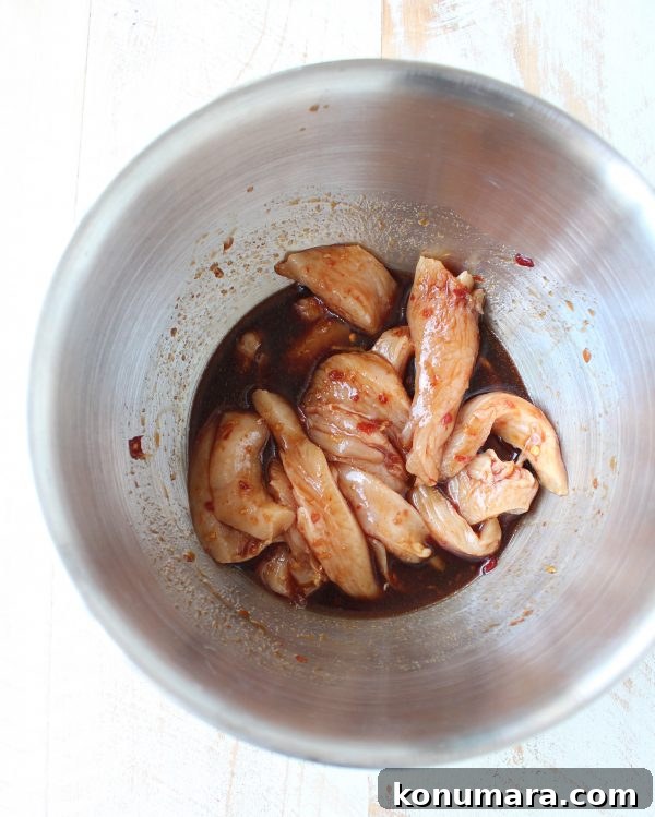 Chicken Lo Mein Recipe: Quick Weeknight Stir Fry 5 raw chicken strips tossed in sauce in a mixing bowl