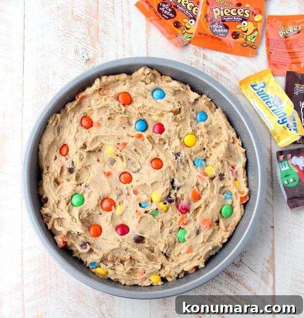 The Ultimate Candy Cookie Cake recipe is perfect for Halloween, birthdays or holidays, add your favorite candy to cookie dough & bake into a tasty cake!