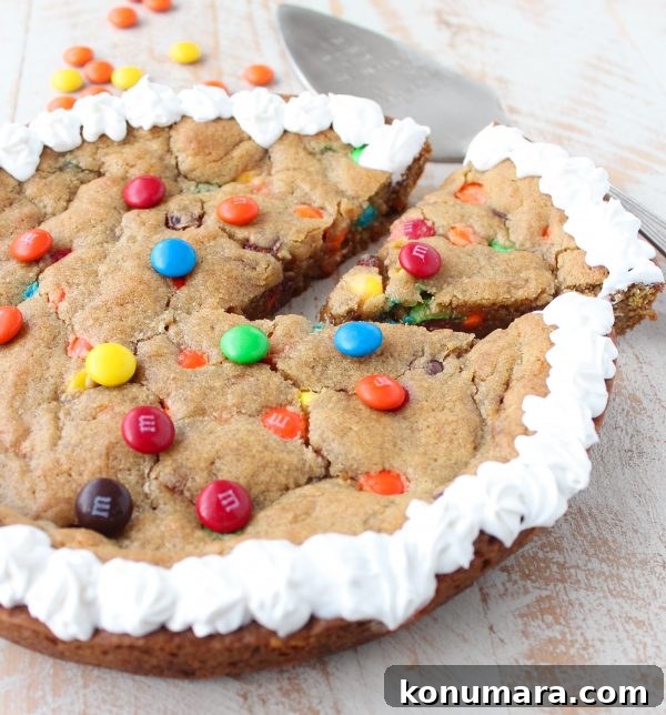 The Ultimate Candy Cookie Cake recipe is perfect for Halloween, birthdays or holidays, add your favorite candy to cookie dough & bake into a tasty cake!