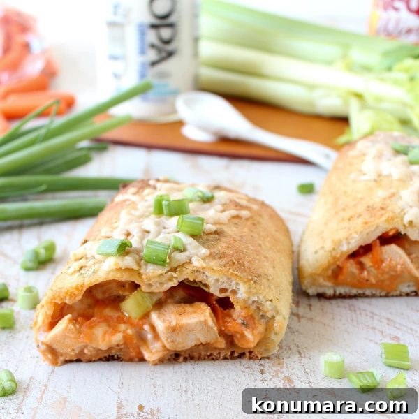 Cheesy Buffalo Chicken Bake Recipe 2 pizza dough stuffed with cubed buffalo chicken cut in half on a wooden surface.