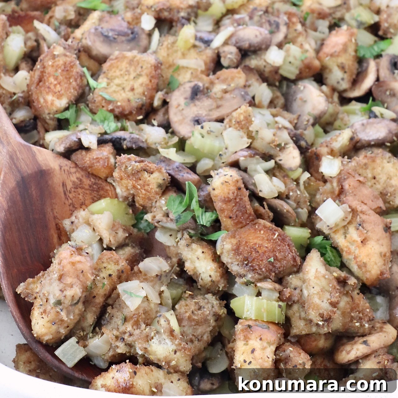 15 Thanksgiving Recipes to Impress Your Holiday Guests 13 mushroom stuffing in a baking dish with a serving spoon