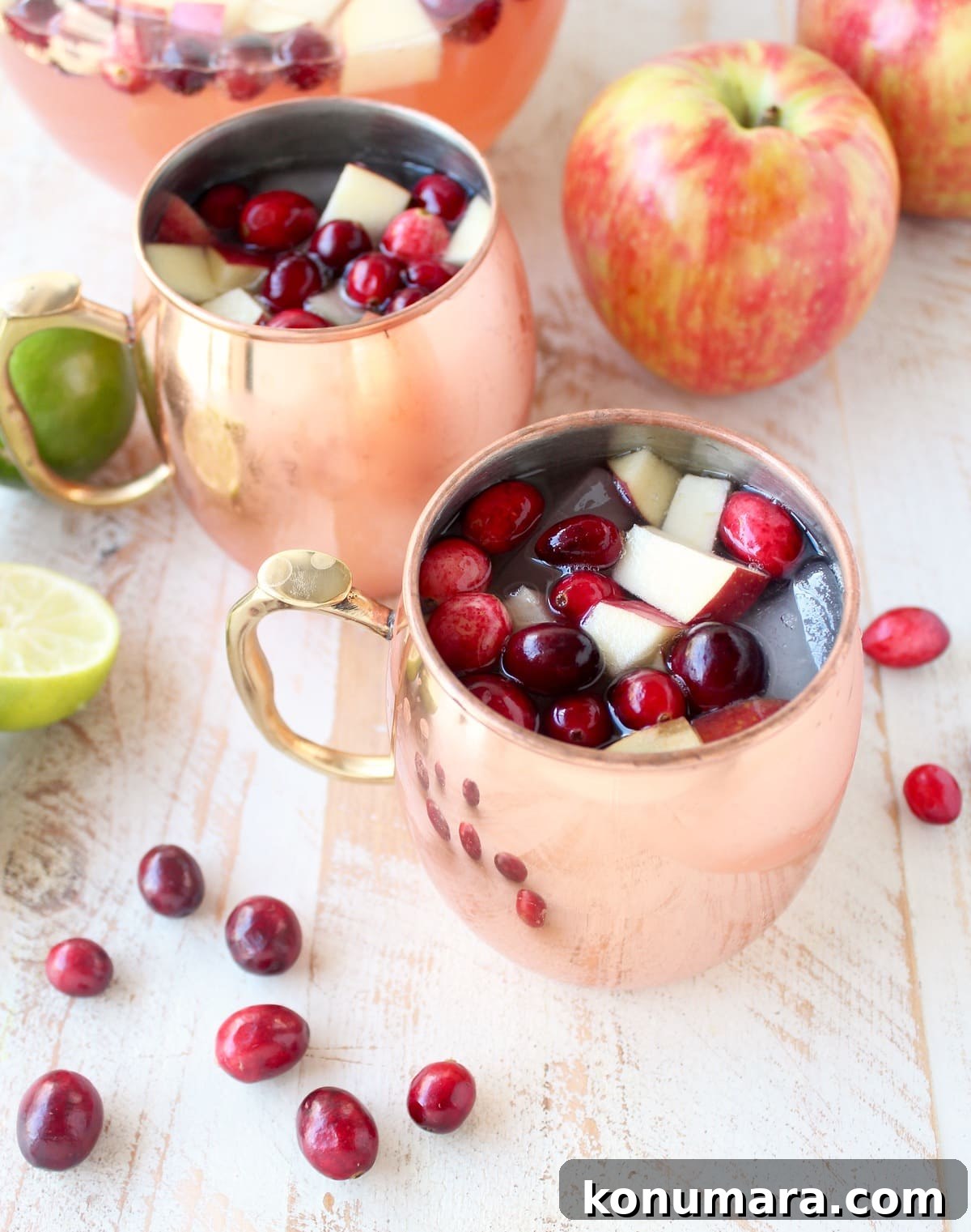 moscow mule punch in copper mugs topped with diced apples and fresh cranberries
