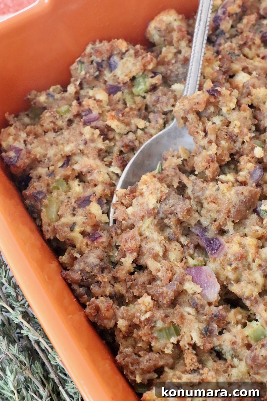 Savory Sausage Stuffing Recipe with Herbs 2 sausage stuffing in an orange baking dish with a serving spoon