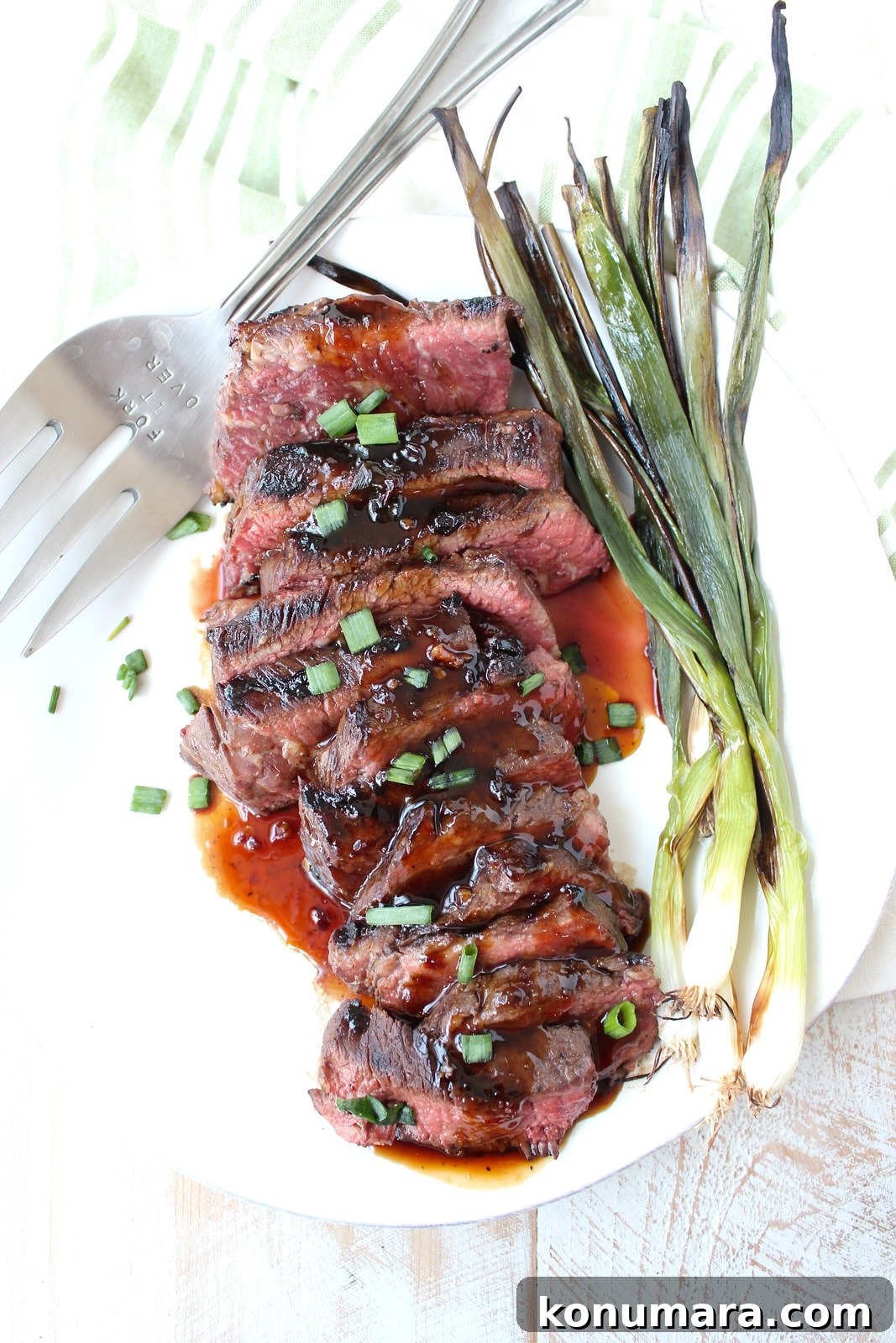 cooked sliced boneless short ribs on a plate with bbq sauce and grilled green onions