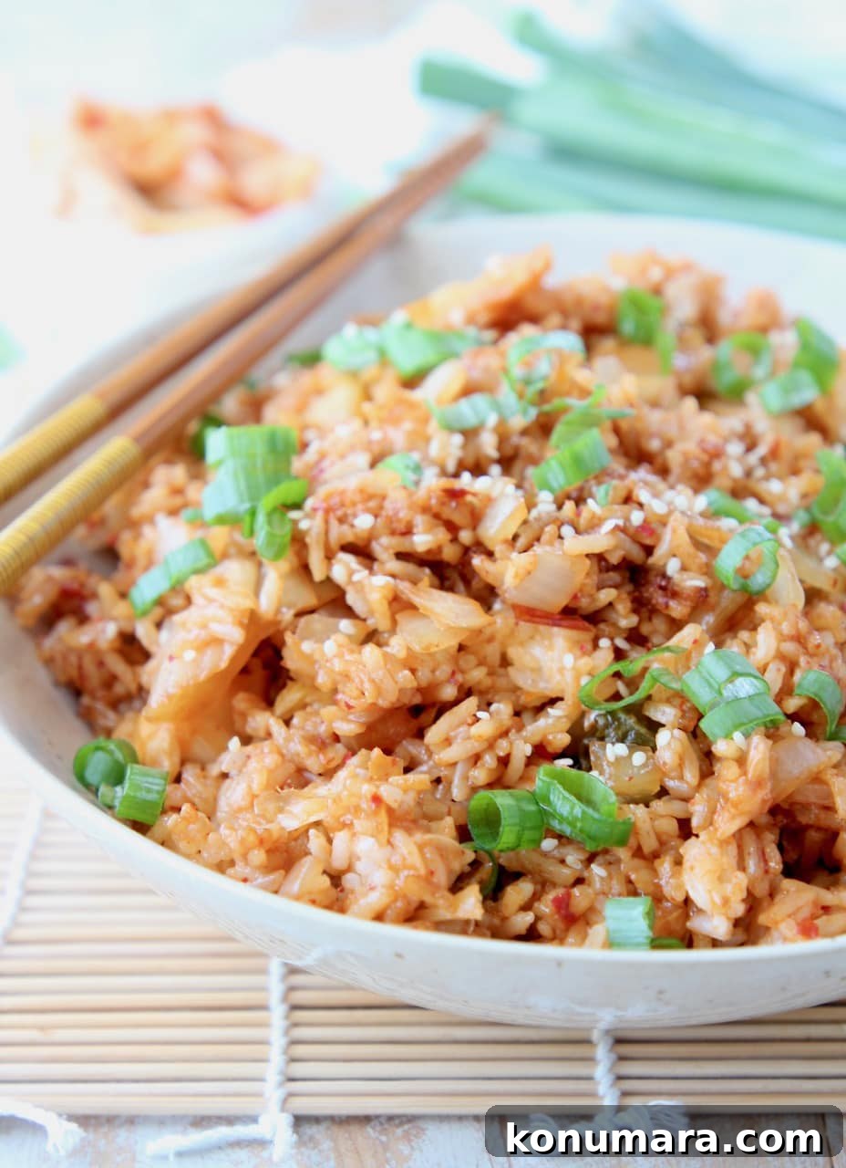 Fried rice in bowl with chopsticks, topped with diced green onions