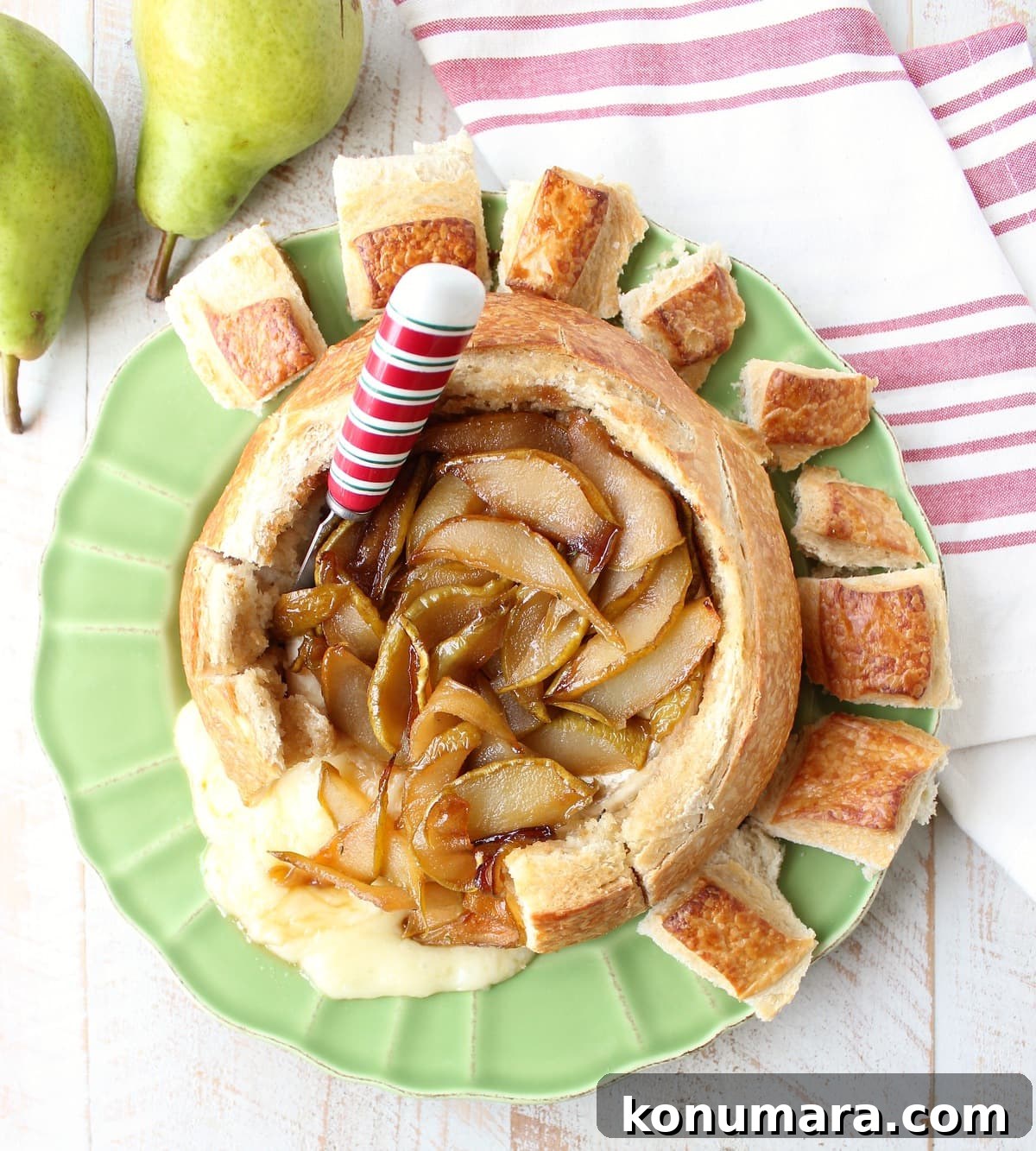 Bread bowl with baked brie, caramelized pears and red, white and green cheese spreader