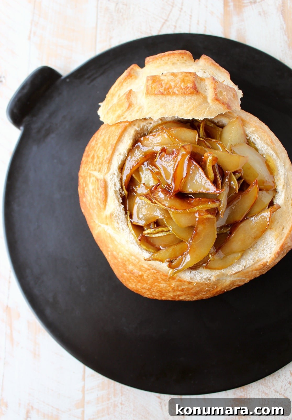 bread bowl on baking sheet filled with brie and caramelized pears