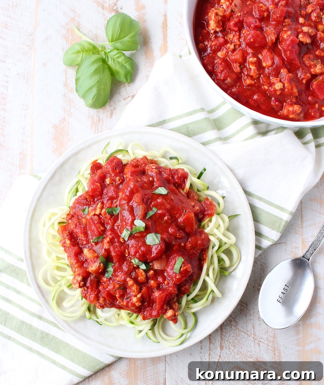 roasted red pepper bolognese sauce in a bowl and served over zucchini noodles on a plate