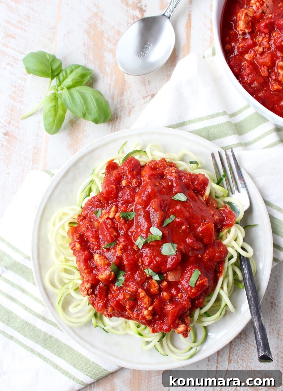 roasted red pepper bolognese sauce in a bowl and served over zucchini noodles on a plate