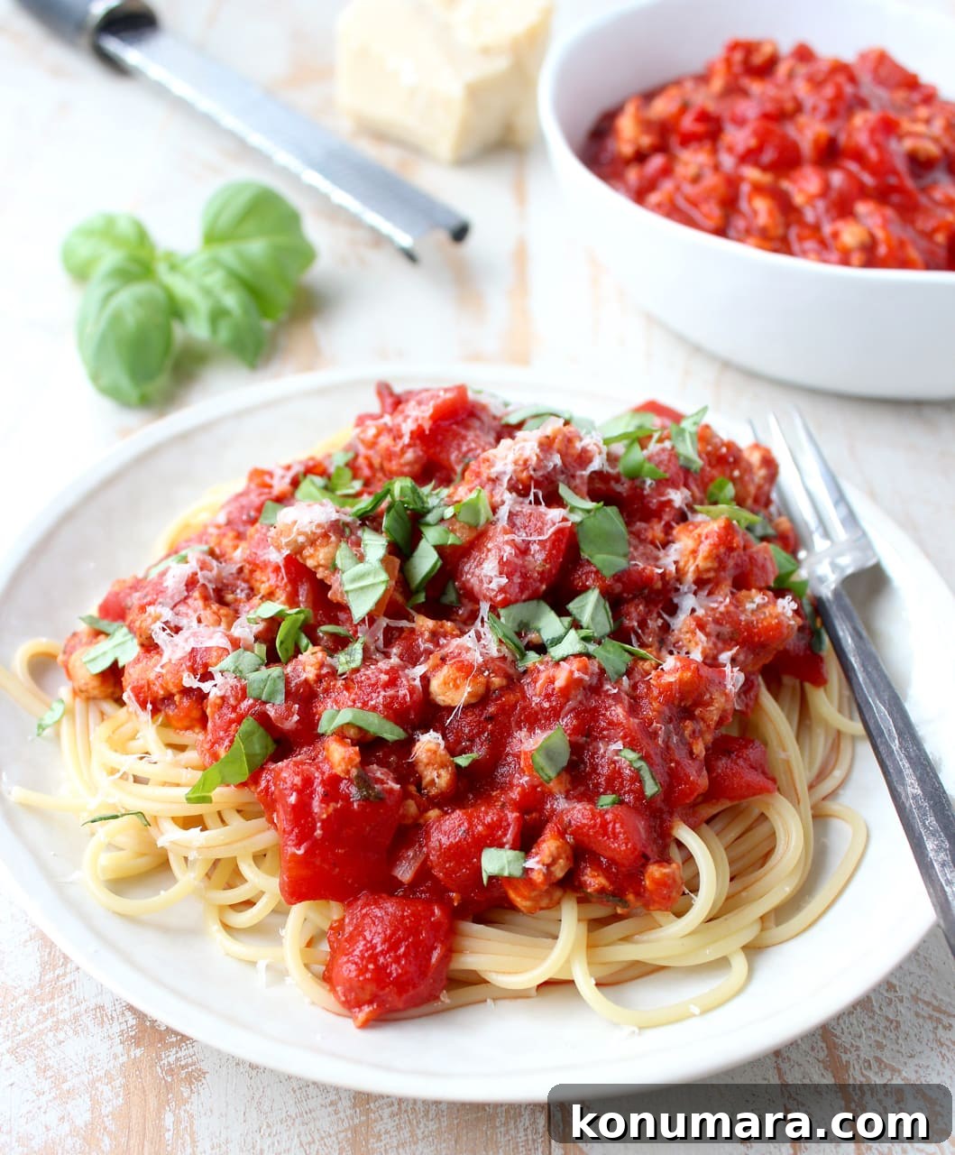 turkey bolognese sauce served over spaghetti noodles on a plate with a fork