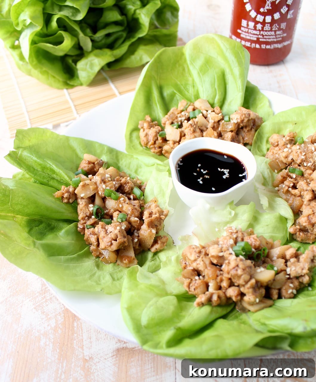 lettuce wraps on a plate filled with a ground turkey mixture with a small bowl of sauce in the middle of the plate