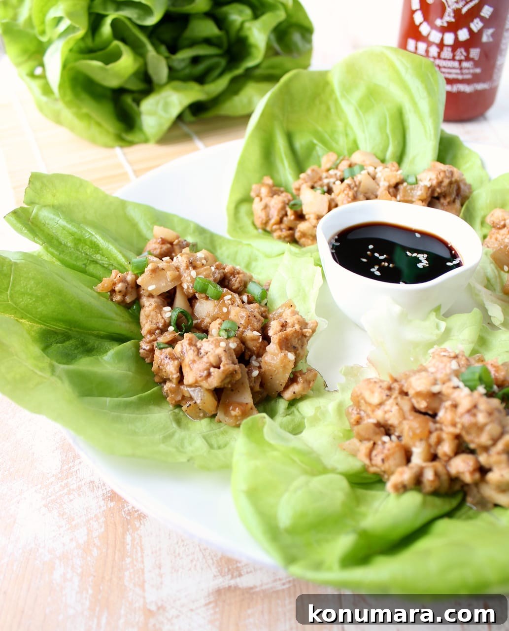 lettuce wraps on a plate filled with a ground turkey mixture with a small bowl of sauce in the middle of the plate