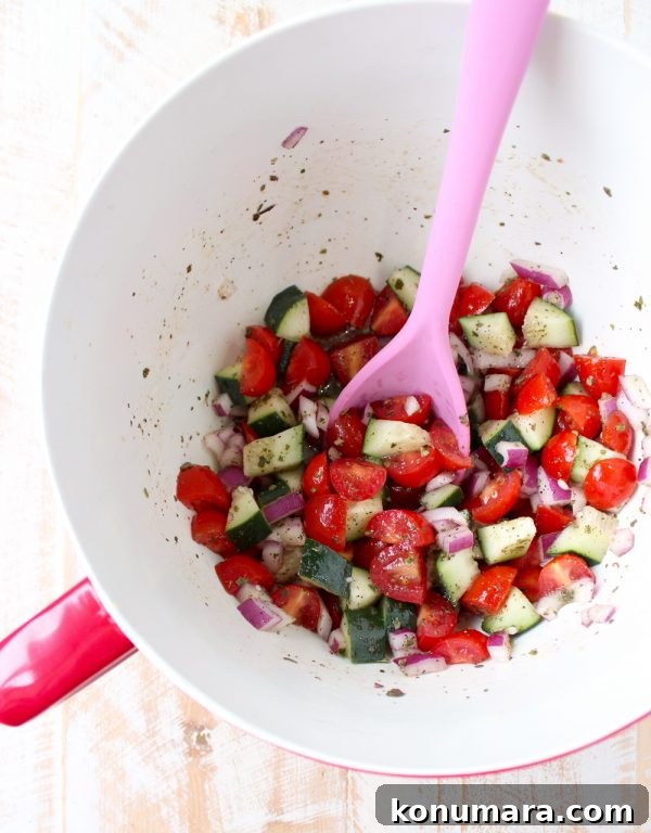 tomato cucumber salad in a large bowl with a pink spoon
