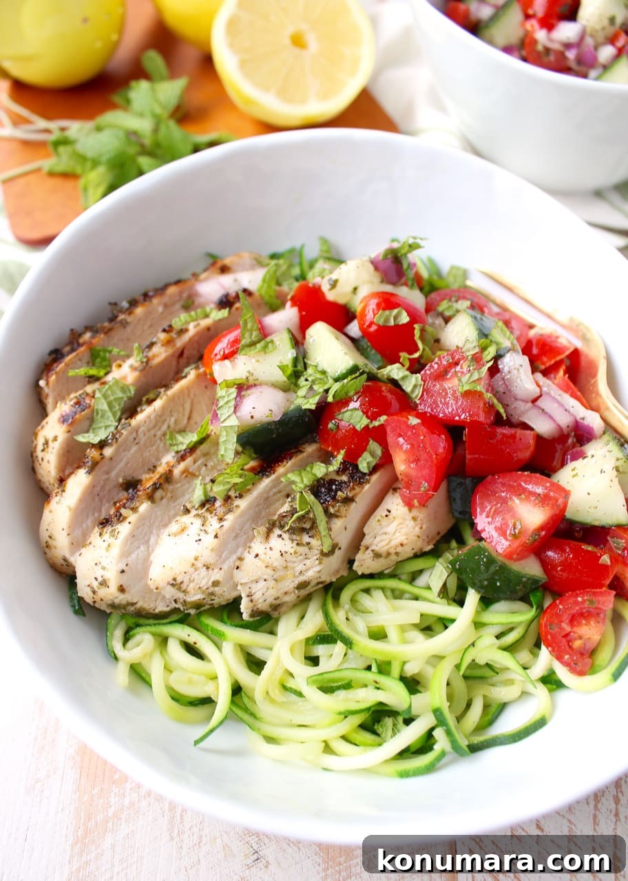 sliced grilled chicken in bowl with zucchini noodles and tomato cucumber salad