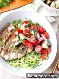 Marinated & grilled Greek Chicken served on a bowl of zucchini noodles topped with cucumber tomato salsa