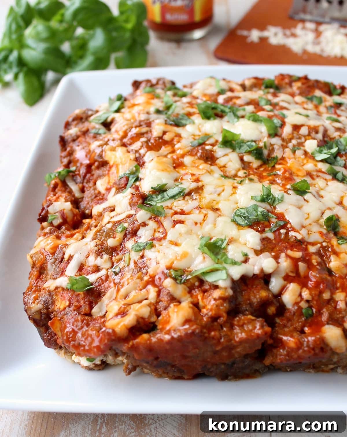 Buffalo-Style Cheesy Meatloaf Recipe 7 meatloaf on plate topped with melted shredded cheddar cheese