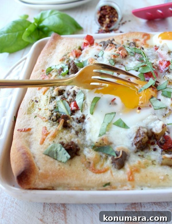 Sheet-Pan Breakfast Pizza Recipe with Eggs and Bacon 3 Close-up of breakfast pizza topped with eggs, turkey sausage, peppers and mozzarella