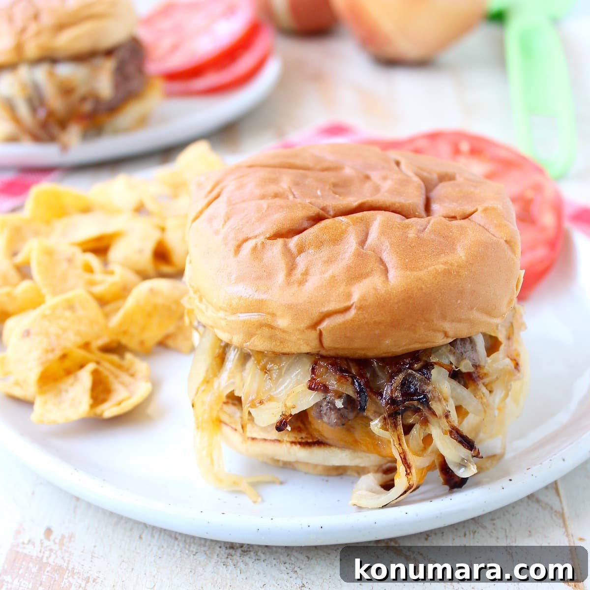 onion fried burger on plate with Fritos chips and sliced tomatoes