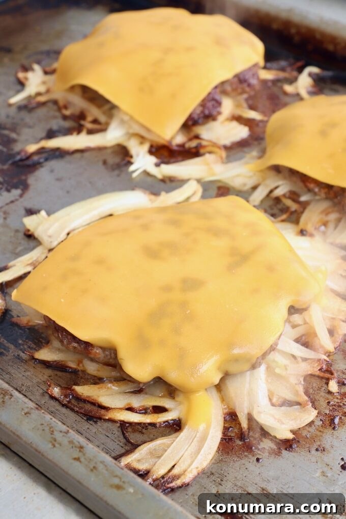 cheese topped fried onion burgers on griddle