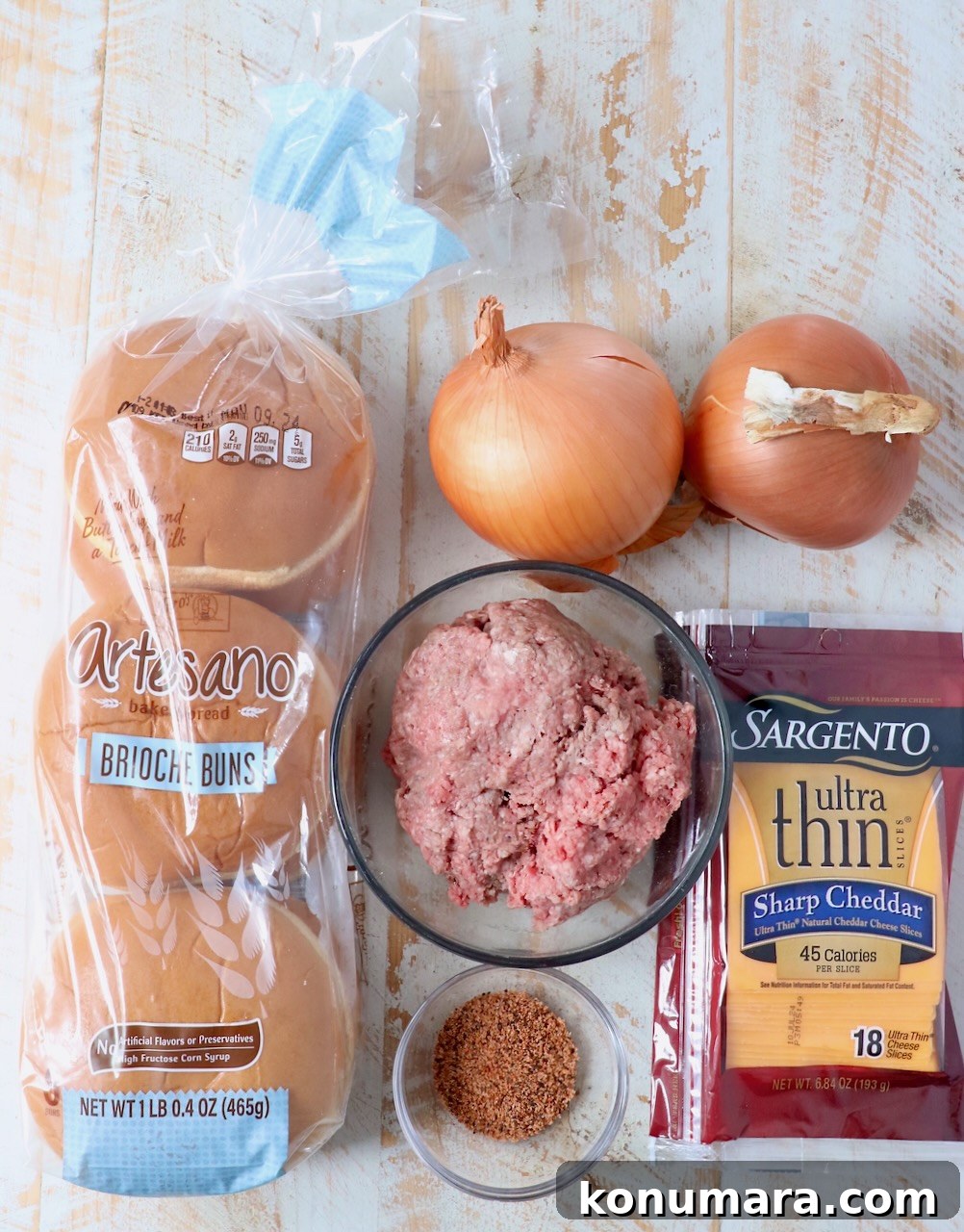ingredients for onion fried burgers on white wood board