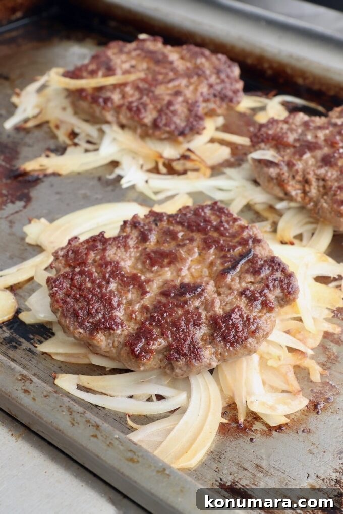 burger patties on top of grilled onions on griddle