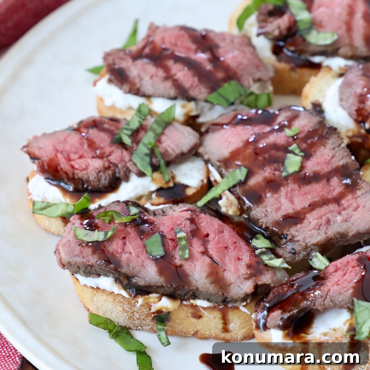 Seared Steak Crostini Recipe with Garlic Herb Butter 2 steak crostini on plate, topped with a drizzle of balsamic glaze