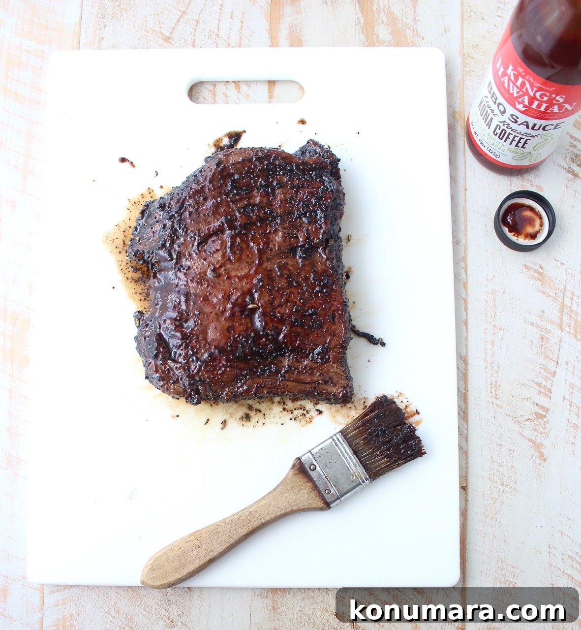 grilled steak covered with bbq sauce on cutting board with pastry brush