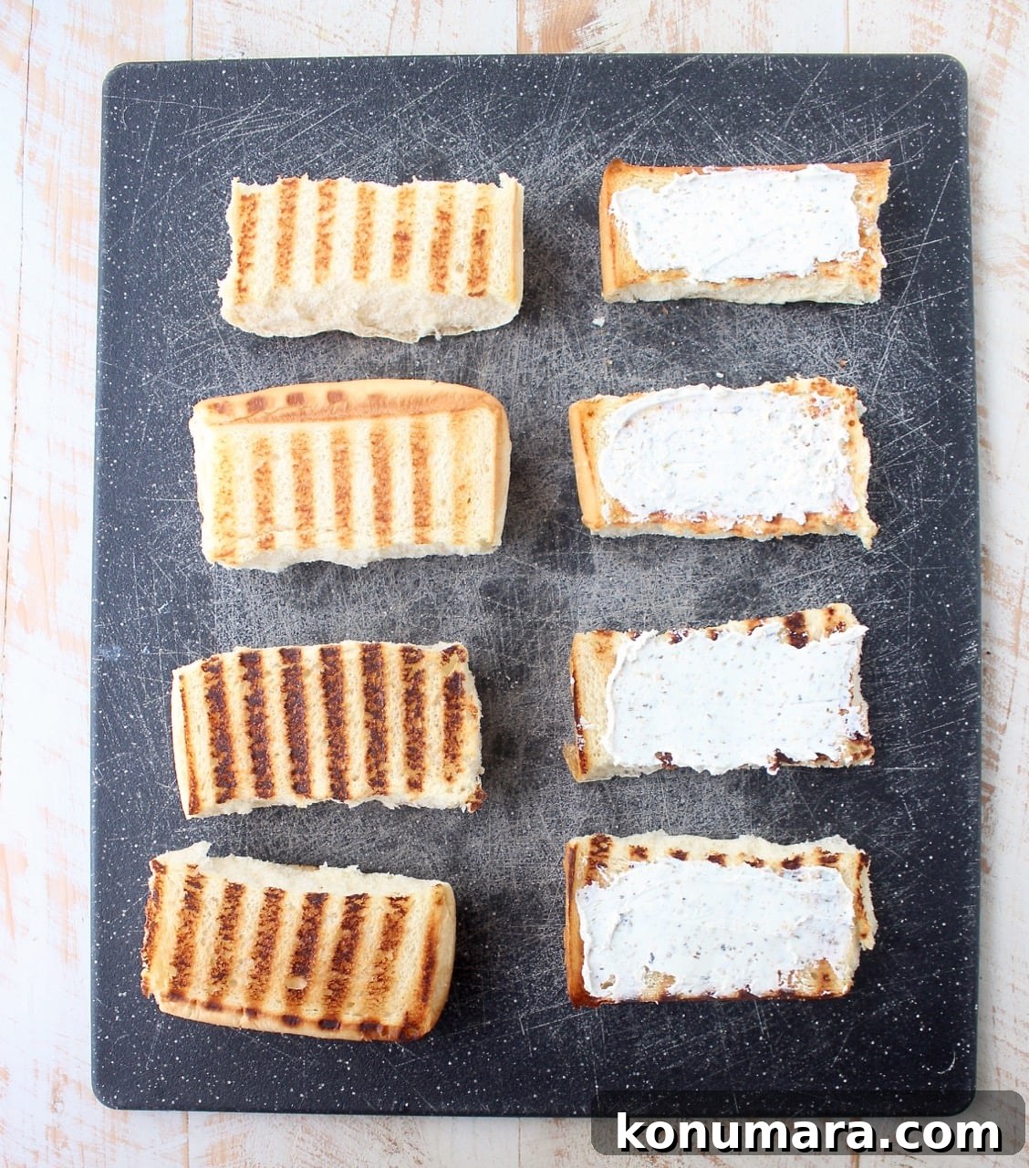 grilled sub rolls on cutting board, half of the rolls topped with herbed goat cheese