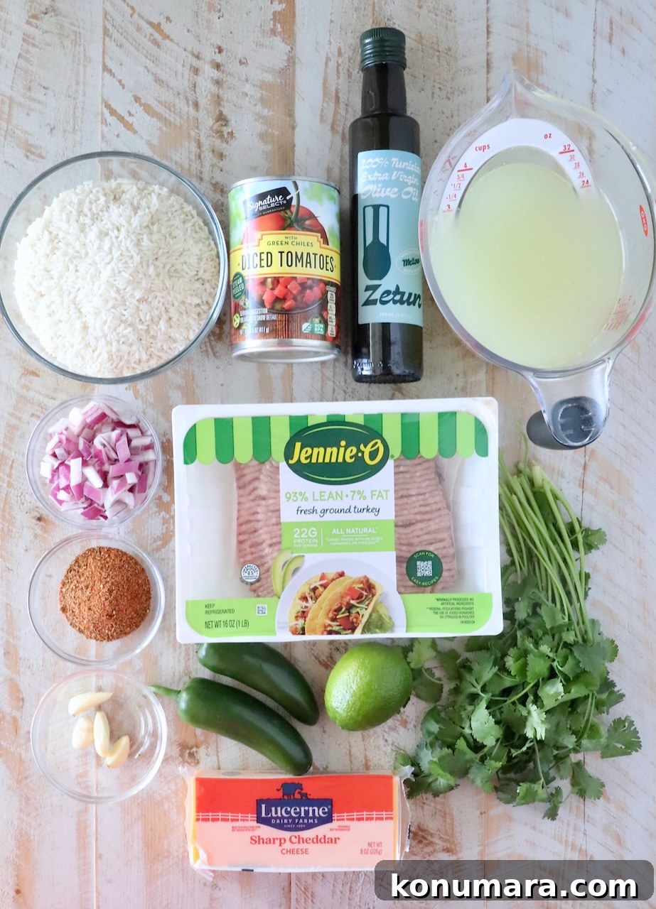 Ingredients for a recipe displayed on a wooden surface include ground turkey, cheddar cheese, diced tomatoes, rice, chicken broth, olive oil, cilantro, lime, jalapeños, garlic, chopped red onion, and a spice mix.