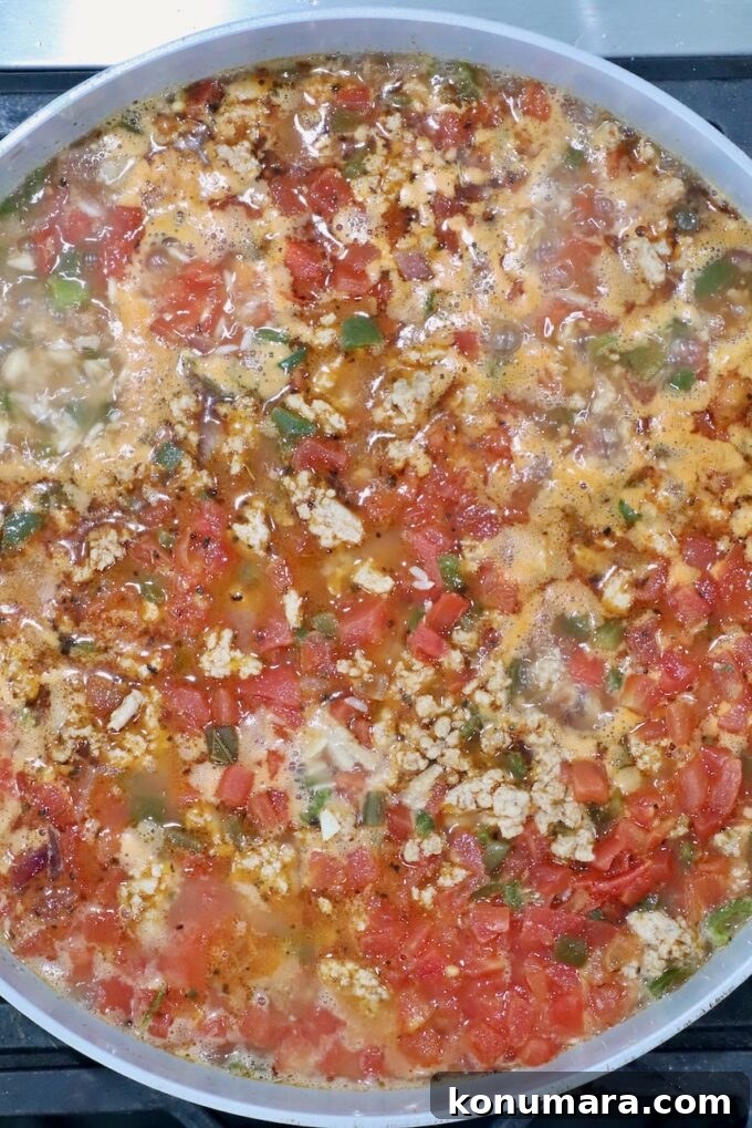 cooked rice, diced tomatoes, and ground turkey in a skillet