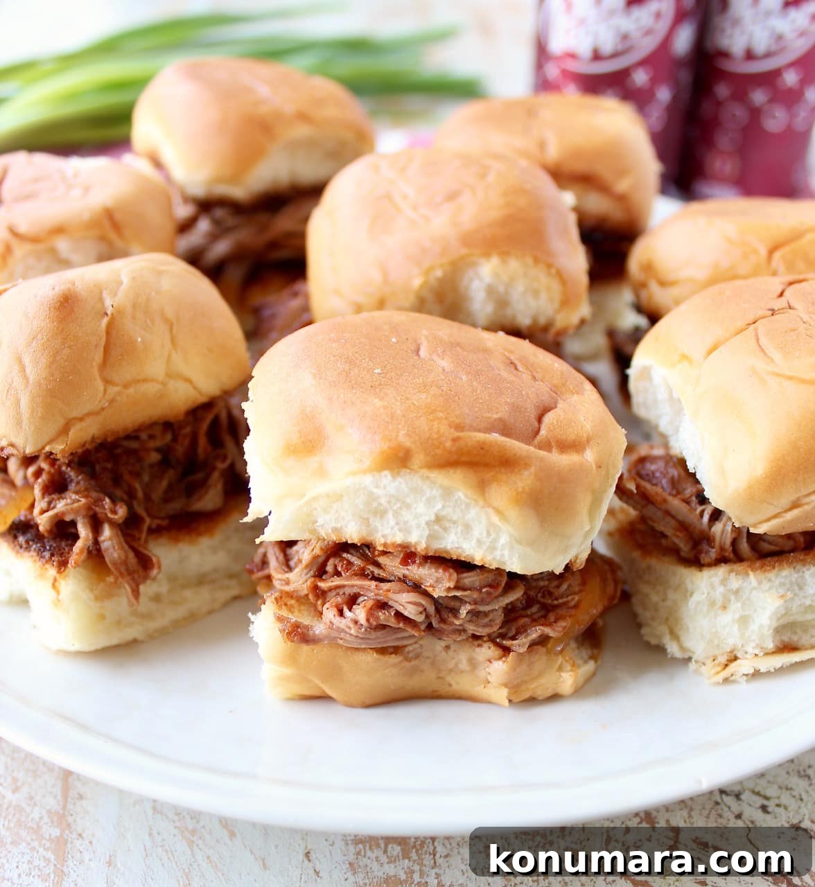Hawaiian rolls filled with shredded Dr Pepper pork on a white plate.