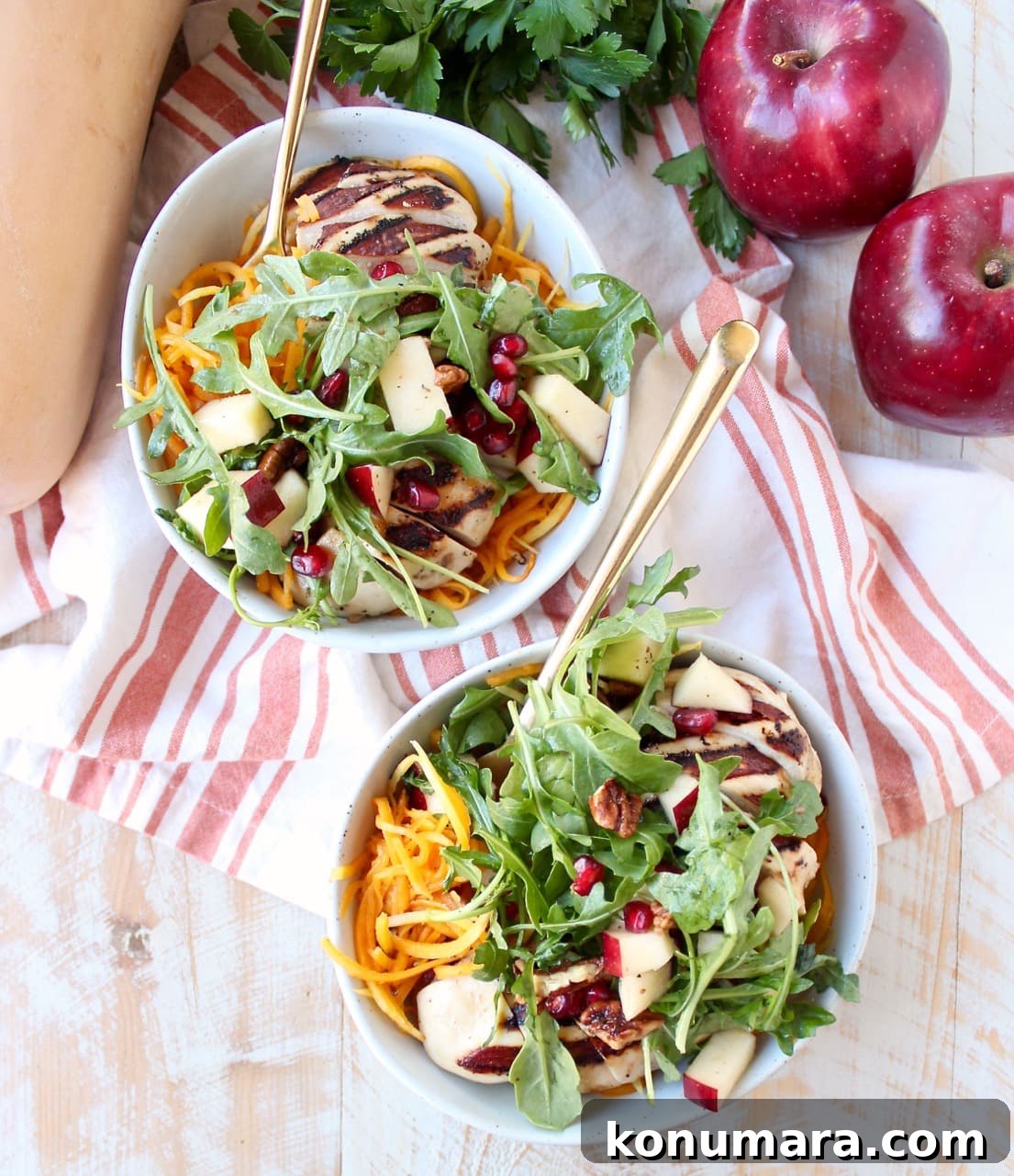 butternut squash noodles, arugula, diced apples, and sliced grilled chicken in two bowls with forks