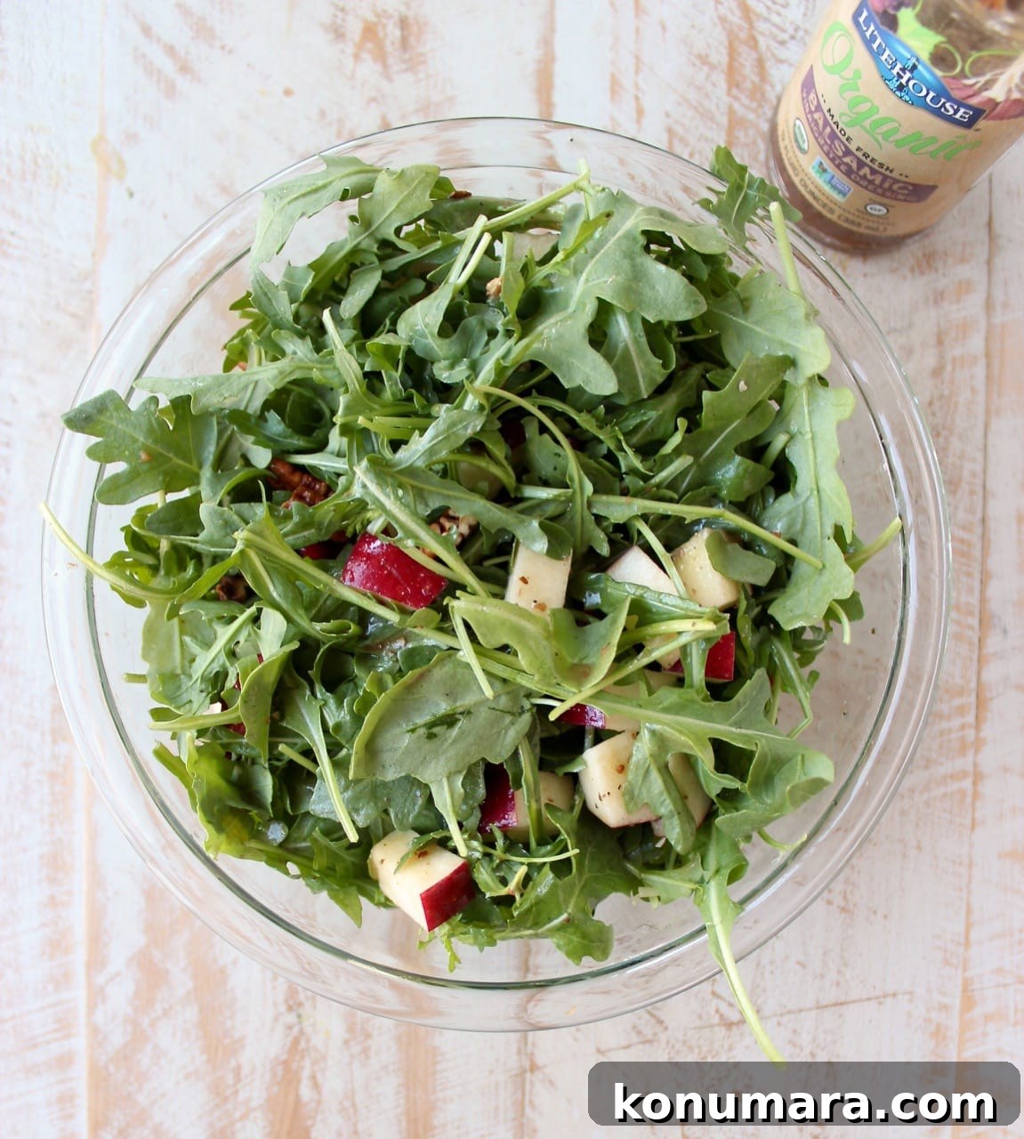 arugula salad with diced apples in a glass bowl