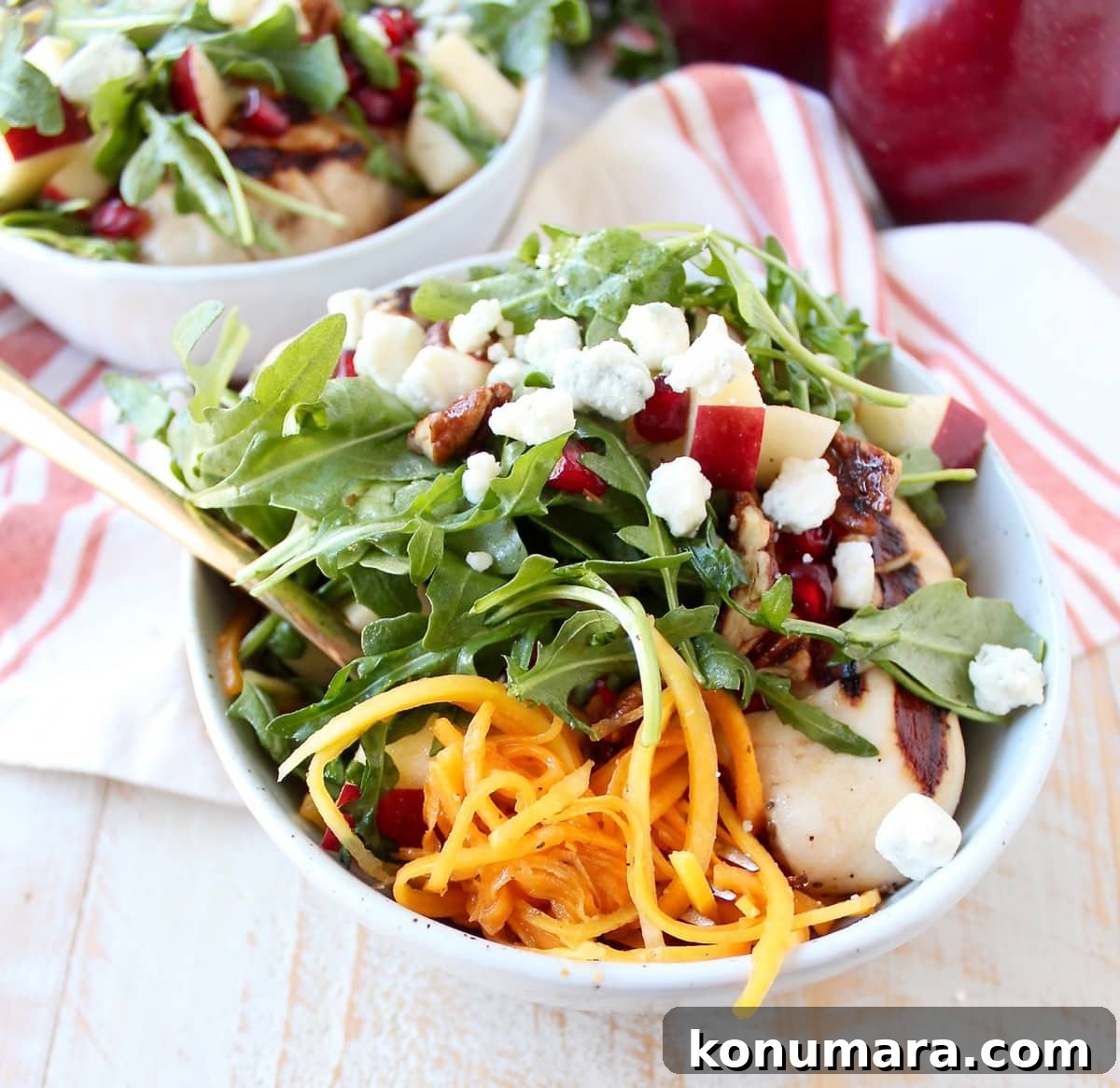 butternut squash noodles, arugula salad with diced apples and grilled chicken in a bowl with a fork