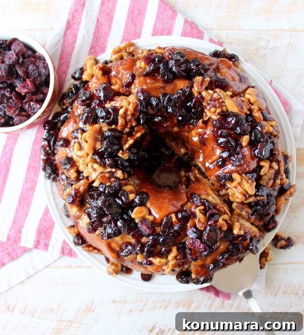 Maple syrup, dried cranberries and walnuts top this decadent monkey bread that's perfect for fall brunches and holiday breakfasts!