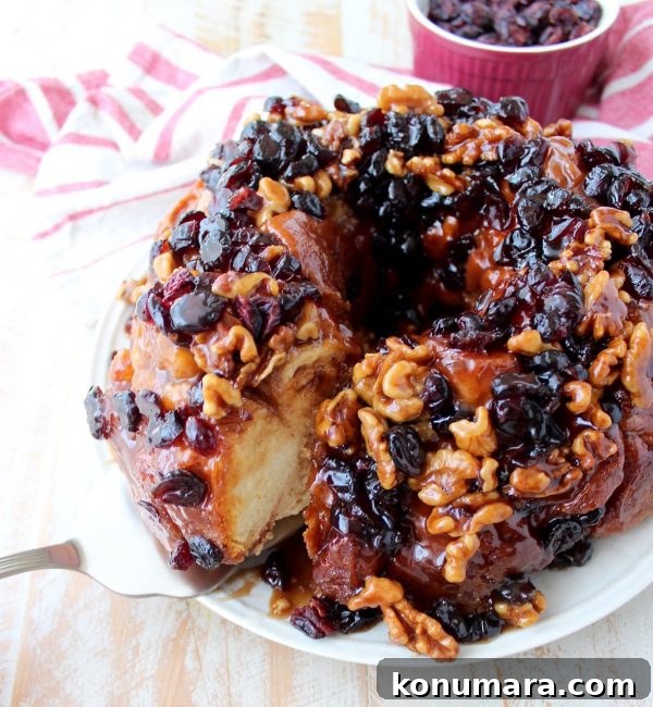 Maple syrup, dried cranberries and walnuts top this decadent monkey bread recipe that's perfect for fall brunches and holiday breakfasts!